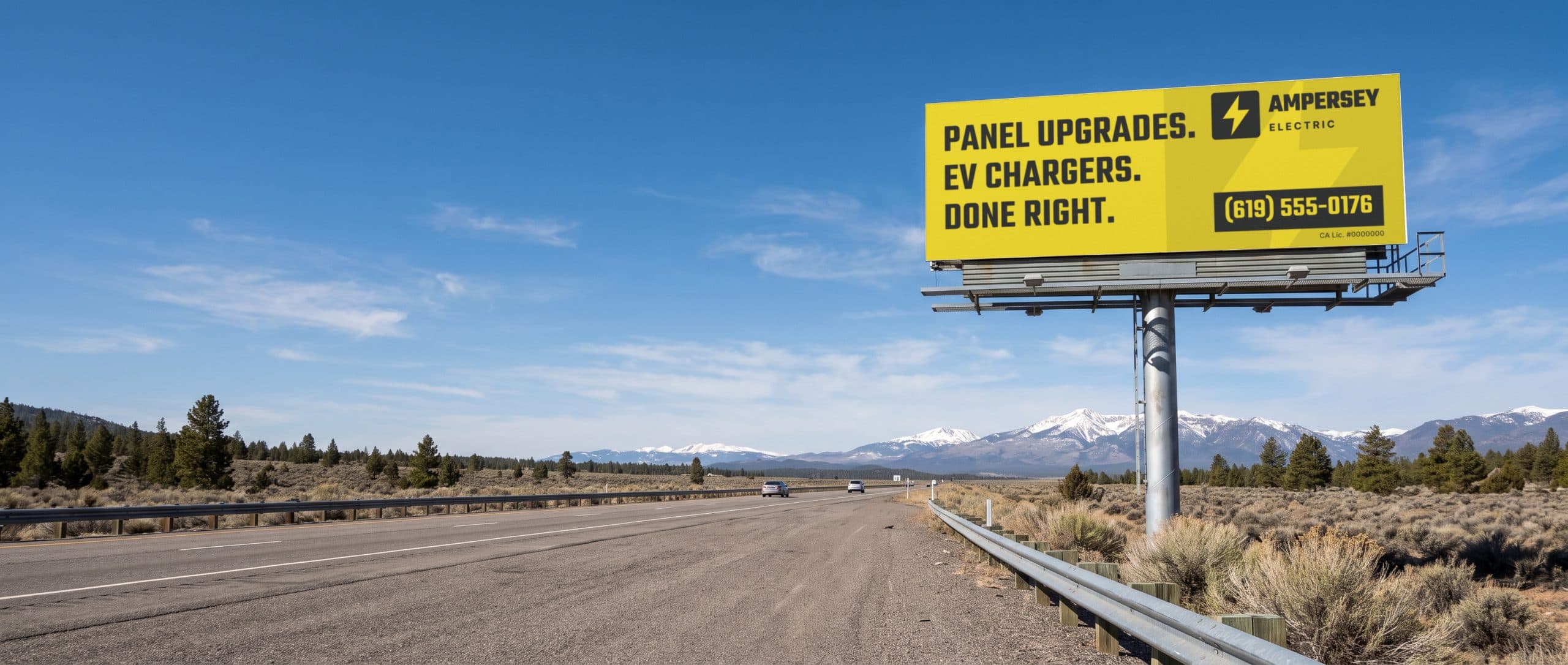 A billboard seen from the highway in clear mountain light, showing a bold, simple electrician ad.