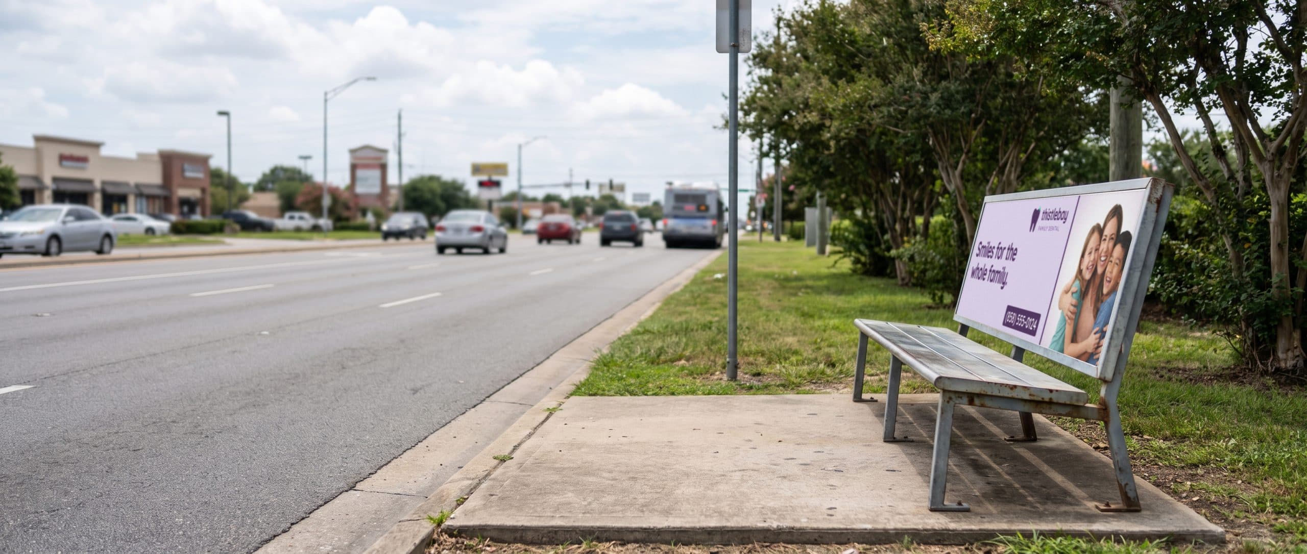 A bus bench beside a busy Southeast road with a family dentist ad on its backrest.