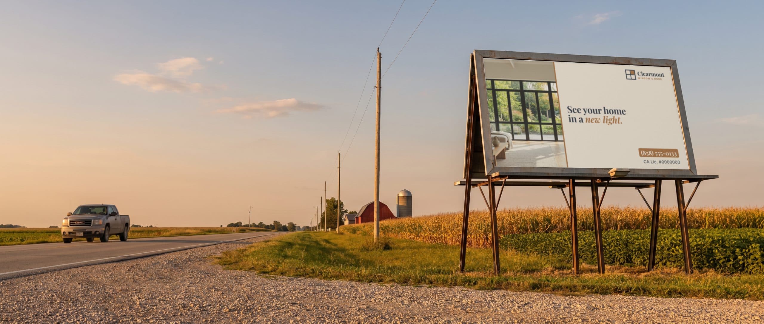 A small poster billboard beside a Midwest farm road, showing a windows and doors company ad.