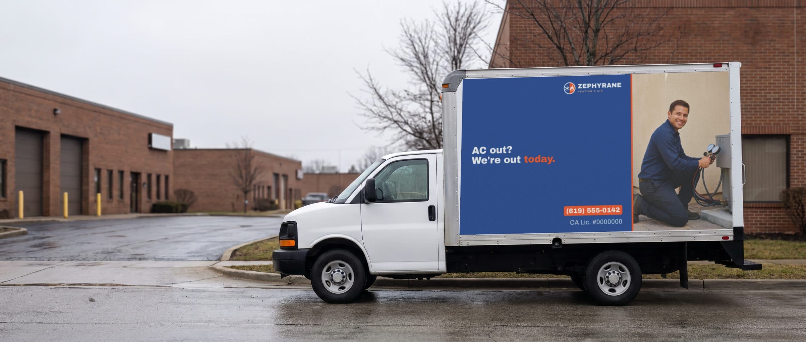A white box truck on a Northeast business road with a heating and air company ad on its side.