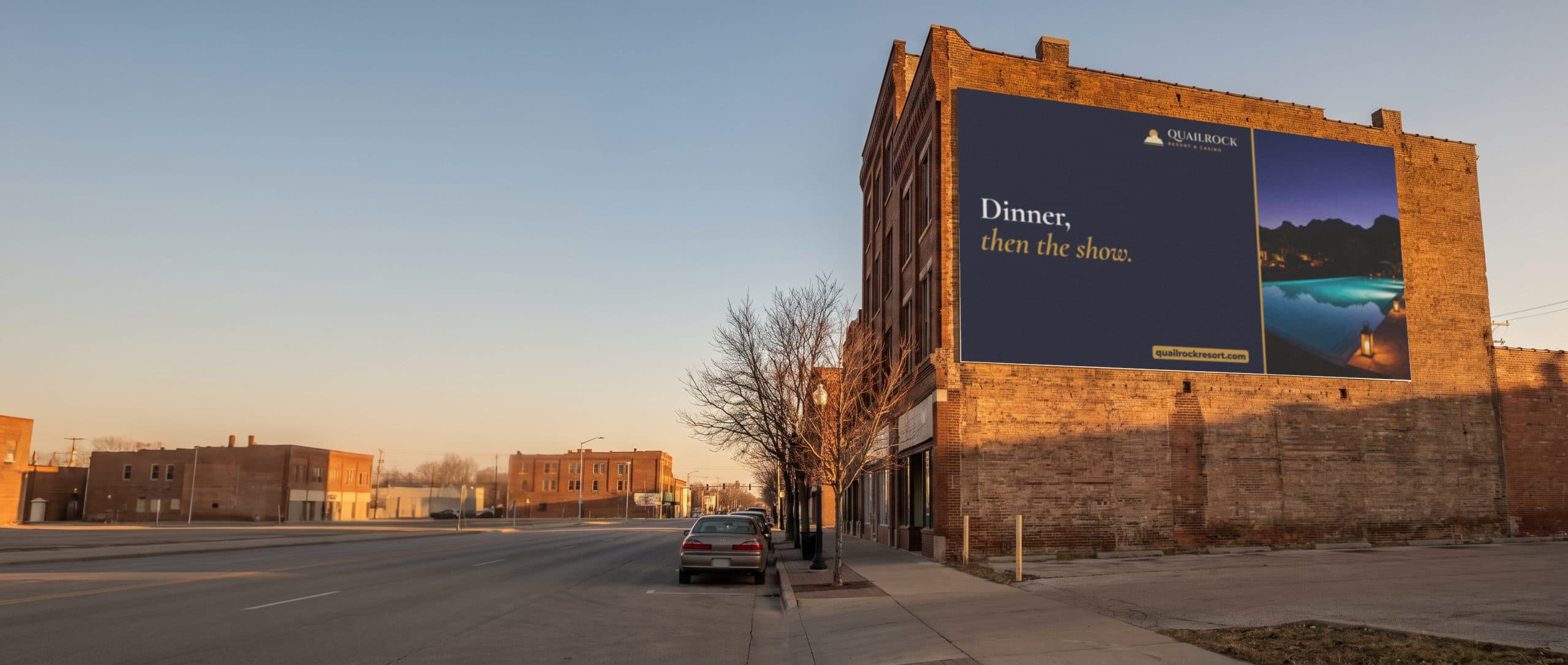 A large painted wall ad on a Midwest brick building at golden hour, promoting a resort.